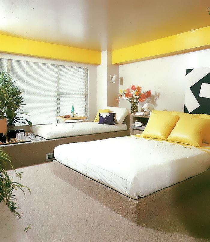 Carpeted platform bed with yellow pillows